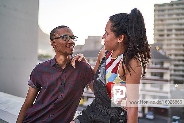 Happy young couple talking on urban rooftop balcony