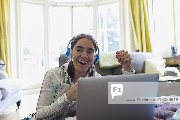 Glückliche Teenagerin mit Kopfhörern Video-Chat am Laptop