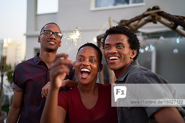 Happy young friends with sparkler on patio