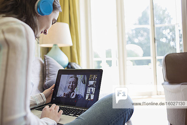 Teenager-Mädchen mit Kopfhörern und Laptop im Video-Chat mit Freunden