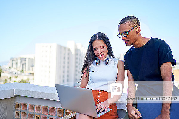Young business people with laptop working on urban rooftop