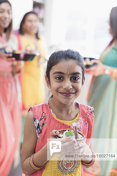 Porträt eines lächelnden indischen Mädchens in Sari und mit Reisschüssel gebunden