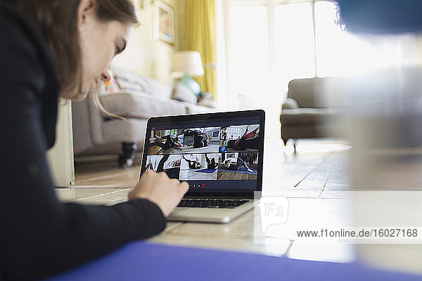 Teenagerin beim Online-Training am Laptop-Bildschirm auf dem Boden