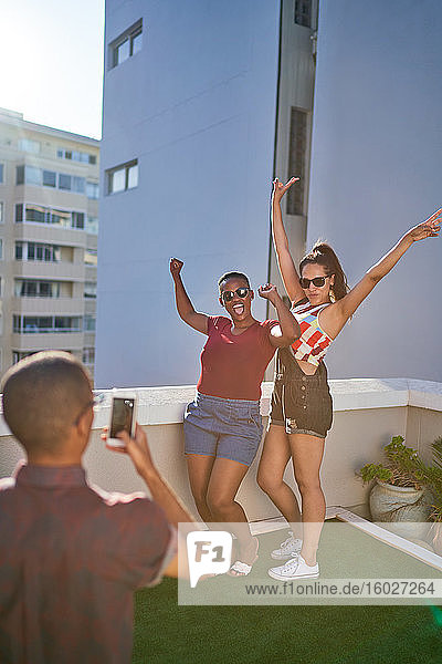 Glückliche junge Freundinnen posieren für ein Foto auf einem sonnigen städtischen Balkon