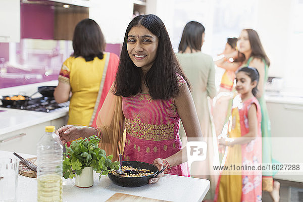 Porträt eines glücklichen indischen Mädchens im Sari beim Kochen in der Küche