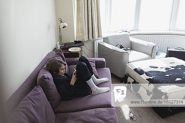 Junge benutzt Smartphone auf Wohnzimmer-Sofa