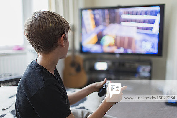 Junge spielt Videospiel am Fernseher im Wohnzimmer