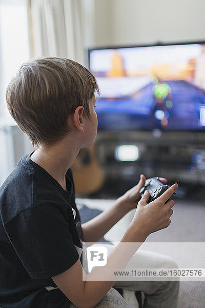 Junge spielt Videospiel beim Fernsehen