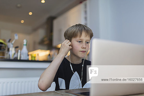 Boy with headphones homeschooling at laptop