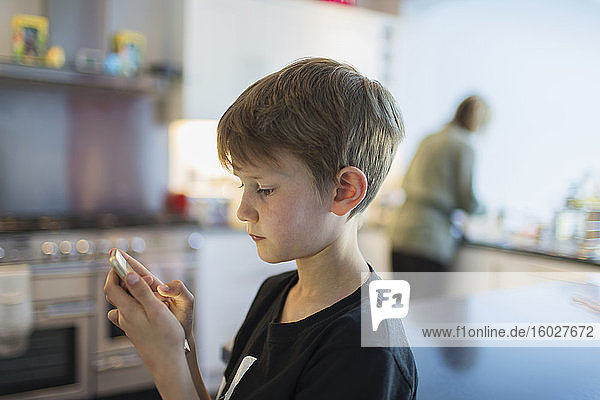 Junge benutzt Smartphone in der Küche