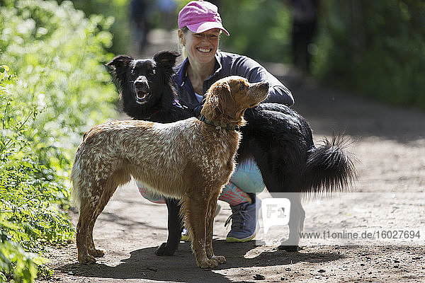 Glückliche Frau mit Hunden auf Wanderweg