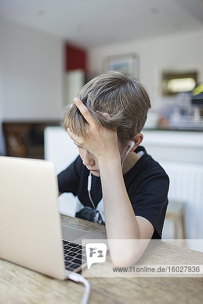 Junge mit Kopfhörern beim Heimunterricht am Laptop