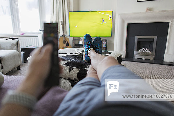 POV-Mann auf Sofa mit Fernbedienung sieht Fußballspiel im Fernsehen