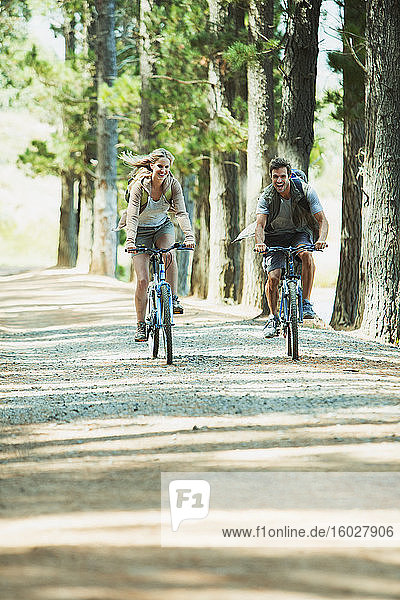 Couple riding mountain bikes in woods