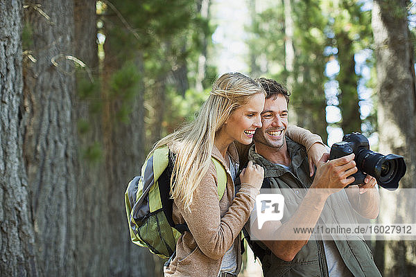 Ehepaar betrachtet Digitalkamera im Wald