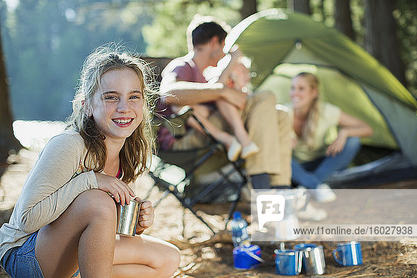 Lächelndes Mädchen auf einem Campingplatz mit Familie im Wald