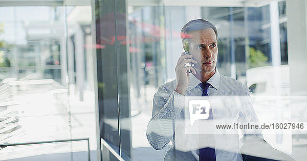 Geschäftsmann telefoniert mit Handy am Bürofenster