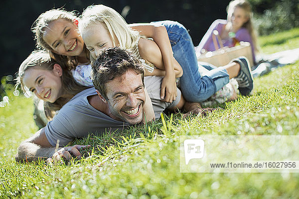Daughters tackling father in grass