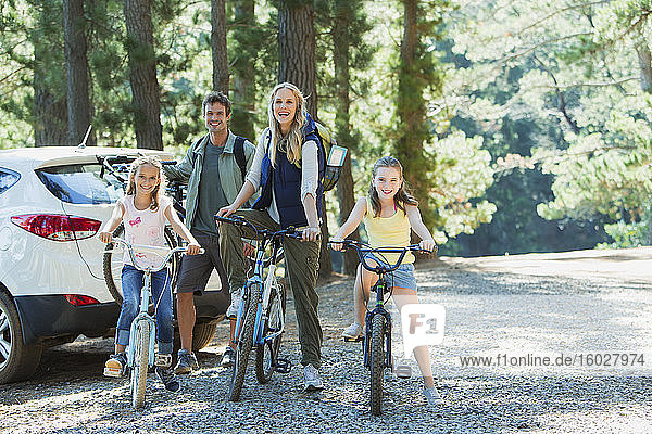 Smiling family with bicycles in woods