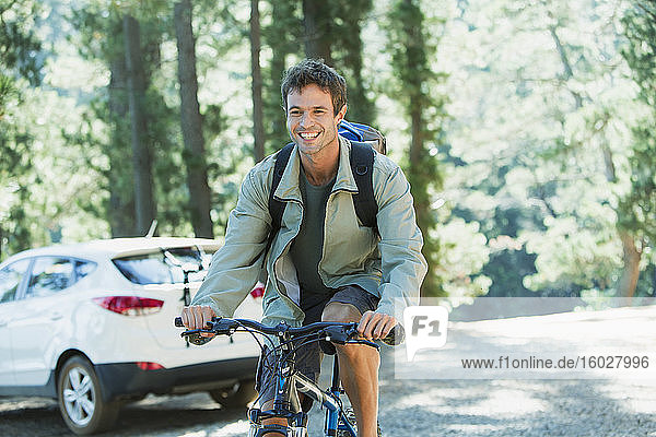 Smiling man riding mountain bike in woods
