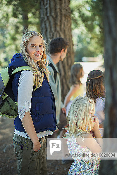 Smiling woman hiking with family in woods