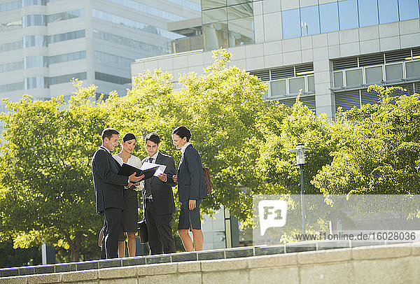 Geschäftsleute diskutieren im Freien über Papierkram