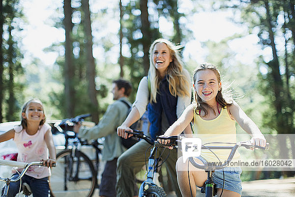 Smiling family bike riding in woods