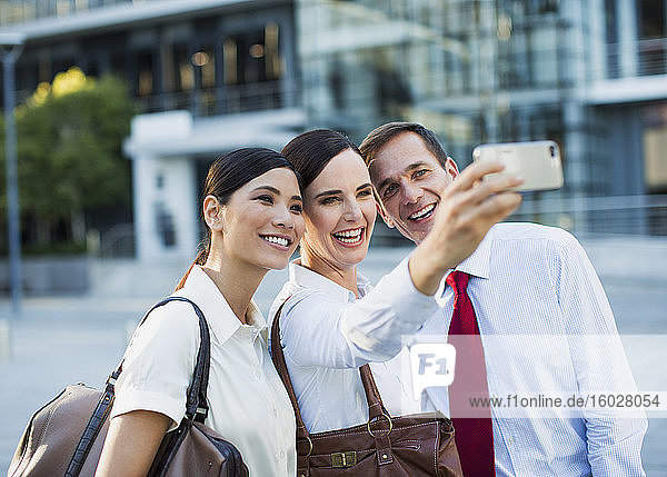 Smiling business people taking self-portrait outdoors