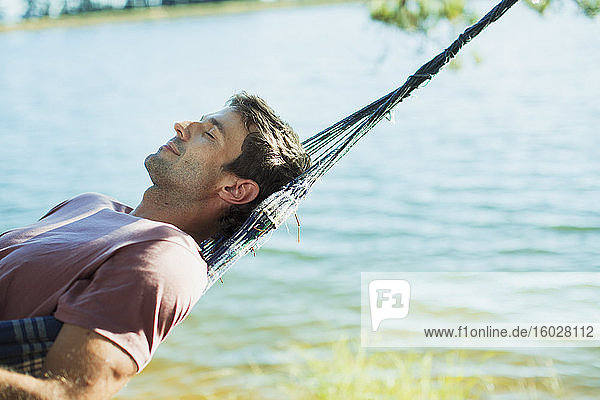 Serene man laying in hammock at lakeside