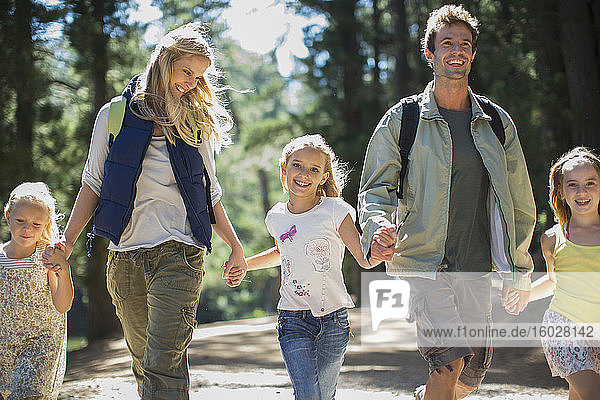 Smiling family holding hands and walking in woods