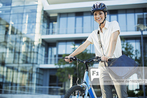 Geschäftsfrau mit Fahrrad vor einem städtischen Gebäude