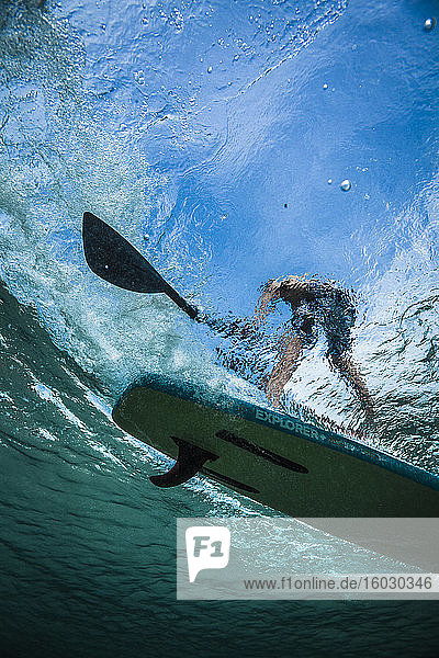 A shot of a person on a paddleboard taken from underwater.