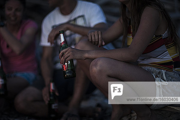 Eine Gruppe junger Leute versammelte sich an einem Strand und trank Bier.