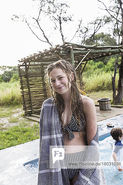Smiling Thirteen year old girl by a swimming pool in a safari resort.