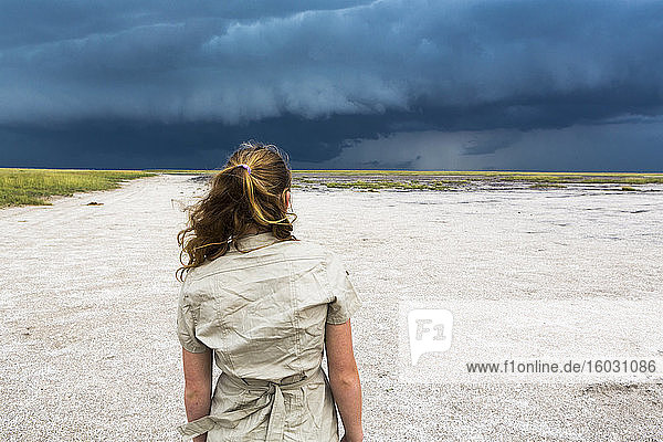 Rückansicht eines dreizehnjährigen Mädchens mit Blick auf den dramatischen Himmel  Nxai Pan  Botswana