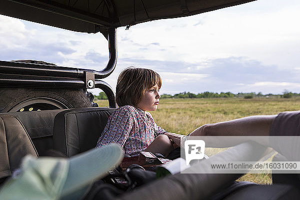 A five year old boy on safari  in a jeep in a game reserve