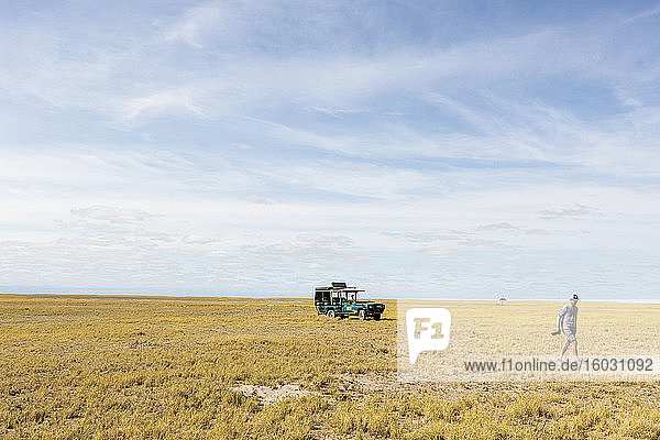 A person walking away from a safari vehicle  Kalahari Desert