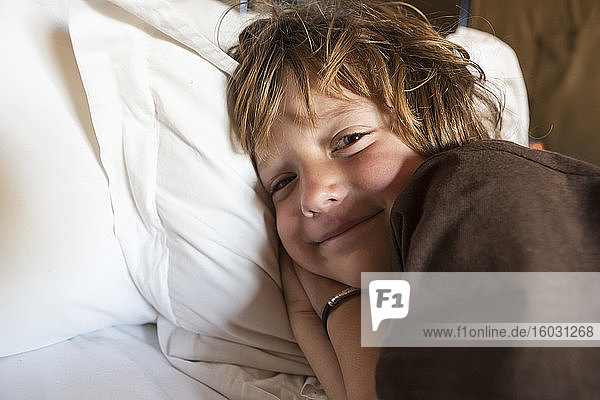 Ein lächelnder 5 Jahre alter Junge im Bett in seinem Zelt Kalahari-Wüste.