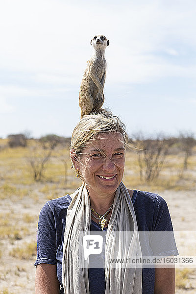 erwachsene Frau mit Erdmännchen auf dem Kopf  Kalahari-Wüste  Makgadikgadi-Salzpfannen  Botswana