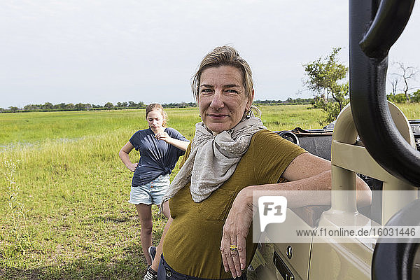 Porträt einer erwachsenen Frau  die sich auf ein Safari-Fahrzeug lehnt  Botswana
