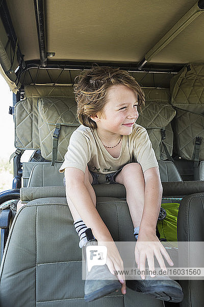 Ein lächelnder sechsjähriger Junge im Safari-Fahrzeug