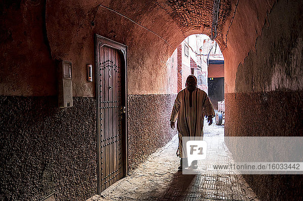 Local man dressed in traditional djellaba walking through archway in a street in the Kasbah  Marrakech  Morocco  North Africa  Africa