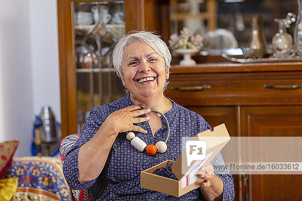 Ältere Frau mit Geburtstagsgeschenk  Online-Feier mit ihrer Familie während der Coronavirus-Sperre.