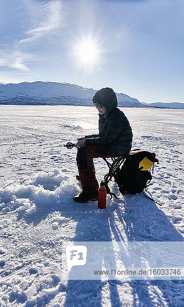 Boy ice-fishing on frozen lake in Vasterbottens Lan  Sweden.