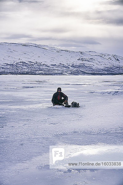 Mann beim Eisfischen auf dem zugefrorenen See in Vasterbottens Lan  Schweden.