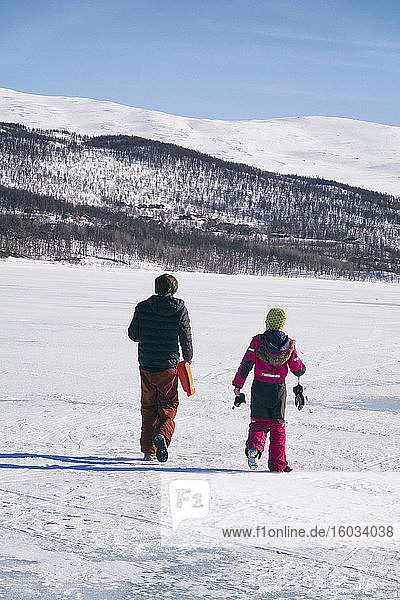 Rear view of two boys walking on frozen lake in Vasterbottens Lan  Sweden.