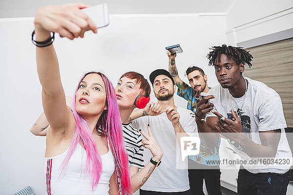 Group of young friends standing indoors  taking selfies.