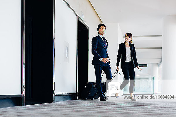 Geschäftsmann und Geschäftsfrau mit Rollgepäck im Hotelgebäude