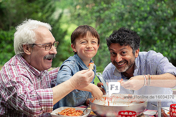 Junge genießt gemeinsam mit Vater und Großvater eine Mahlzeit