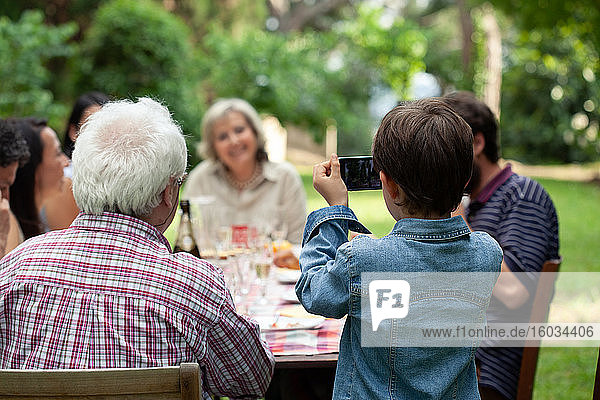 Junge fotografiert Familie beim Essen im Freien